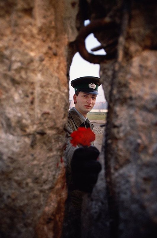 18. На снимке охранник просовывает цветок в отверстие в Берлинской стене, которая утром этого дня была снесена. 1989 год. Источник: reddit.