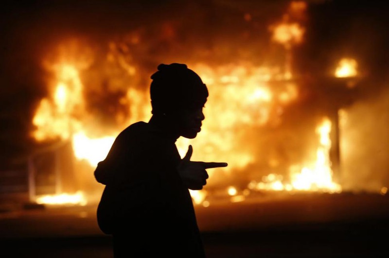 4 Jim Young. A man walks past a burning building during rioting after a grand jury returned no indictment in the shooting of Michael Brown in Ferguson, November 25, 2014.