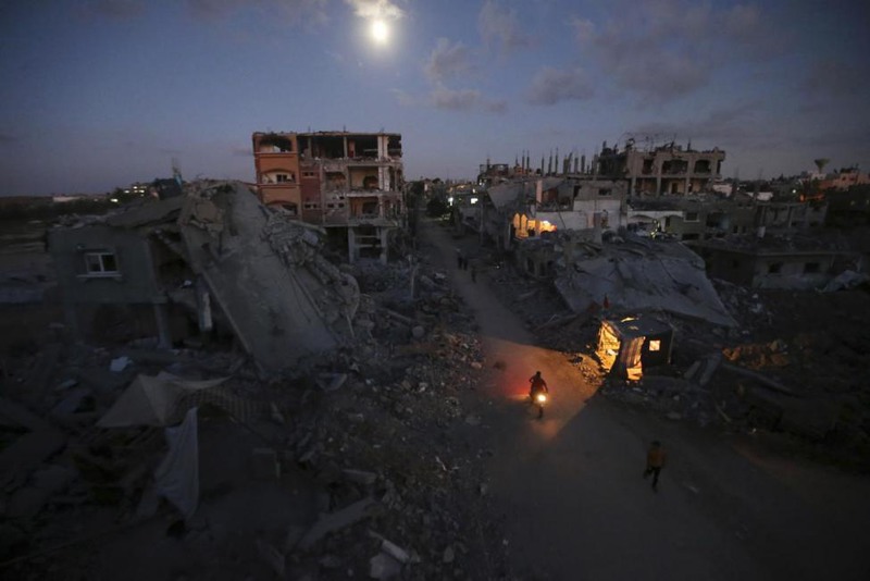 16 Mohammed Salem. Palestinian pedestrians and a motorcyclist commute along a road between the ruins of houses in Beit Hanoun town in the northern Gaza Strip, September 7, 2014.