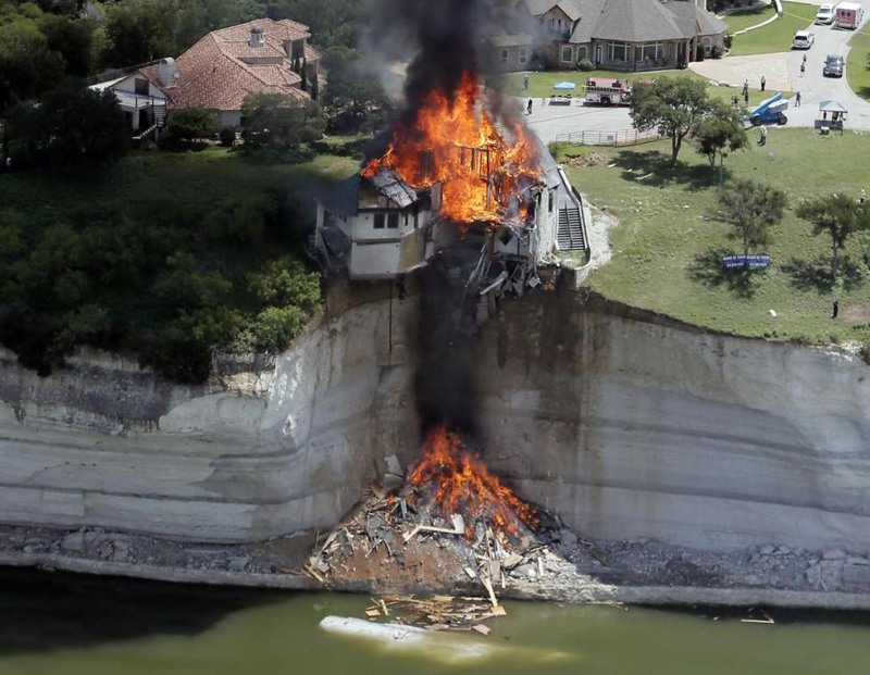 18 Brandon Wade. Smoke rises from a house days after part of the ground it was resting on collapsed into Lake Whitney, Texas, June 13, 2014