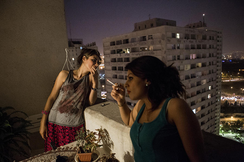 3 Молодые девушки, курящие на балконе своего дома. В таком виде (в майках и с непокрытой головой) они могут пребывать только дома.