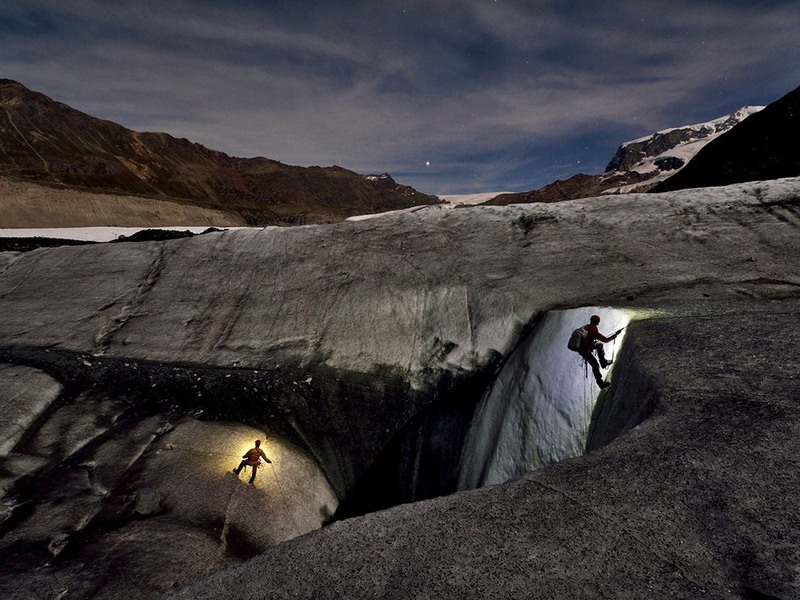 3. Двое исследователей спускаются в ледяные глубины ледниковой «мельницы» в Швейцарии, чтоб определить изменения, которые происходят под землей. Эти работы производятся ночью, т.к. днем из-за таяния льда это делать опасно. Автор - Robbie Shone.