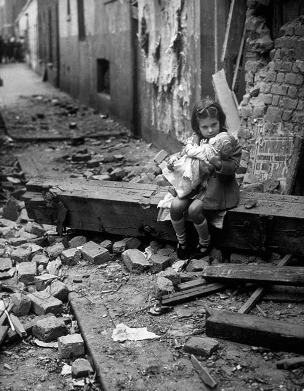 28 Маленькая девочка с куклой сидит в руинах своего дома после бомбёжки, Лондон, 1940.