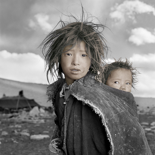 Джигме, 8 лет и Сонам, 18 месяцев. Ладак,Тибет. «Джигме и Сонам — сестры из семьи кочевников, которая только что спустилась с Гималаев в свой зимний лагерь, расположенный на Тибетском плато на высоте 5000 м над уровнем моря. Когда я показал Джигме ее портрет на поляроидном снимке, она вскрикнула и убежала в шатер. Я понял, что она впервые видела себя со стороны, потому что в ее семье нет зеркала».