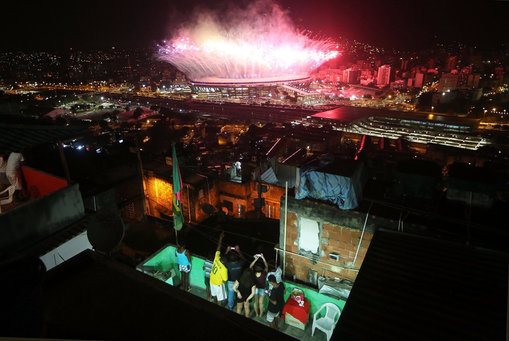 11 августа, Рио-де-Жанейро, Бразилия. Жители фавел любуются салютом на стадионе «Маракана», венчающим церемонию открытия Олимпийских игр. Фото: Mario Tama / Getty Images.