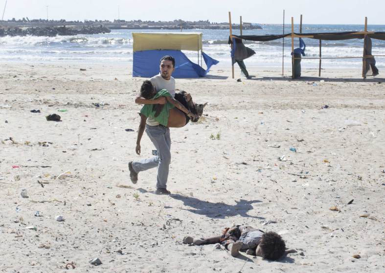 26  Автор - Tyler Hicks—The New York Times/Redux. A man carries a child as another lies dead after two explosions on a beach in Gaza, July 16, 2014.