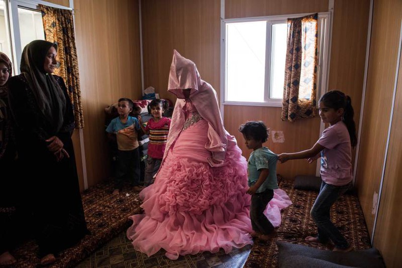 30  Автор - Lynsey Addario—Getty Images Reportage. Rahaf Yousef, 13, a Syrian refugee from Daraa, poses for a portrait in her family's trailer as she is surrounded by female relatives on the day of her engagement party at the Zaatari refugee camp in Jordan, Aug. 29, 2014.