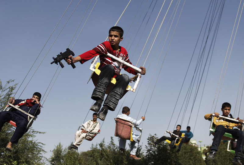 16 An Afghan boy holds a toy gun as he enjoys a ride with others on a merry-go-round to celebrate the Eid al-Fitr festival in Kabul on September 20, 2009. (AP Photo/Anja Niedringhaus)