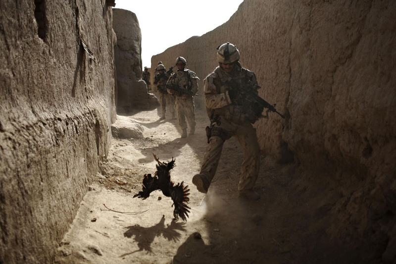 17 A Canadian soldier with the 1st RCR Battle Group, The Royal Canadian Regiment, chases a chicken seconds before he and his unit were attacked by grenades shot over the wall during a patrol in Salavat, southwest of Kandahar, on September 11, 2010. (AP Photo/Anja Niedringhaus)