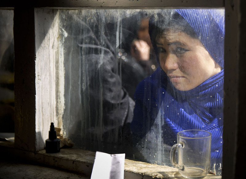 26 An Afghan woman peers through a window where women line up to have their picture taken to register for the upcoming presidential elections in a school in Kabul on March 18, 2014. Last-minute registration of voters continues despite the fact that more than 21 million voter registration cards have been issued while only roughly 12 million Afghans are eligible to vote. The discrepancy is the result of repeated registrations since the first round of elections in Afghanistan in 2004. (AP Photo/Anja Niedringhaus)