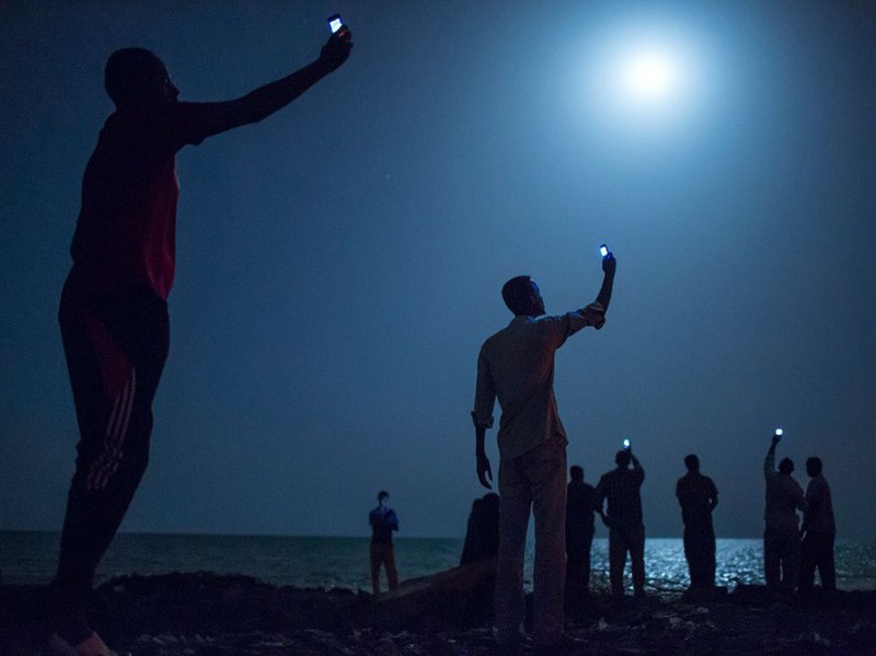 10 Африканские мигранты на берегу города Джибути в поисках сигнала, чтобы связаться с родственниками из соседнего Сомали по мобильному телефону. Автор - Джон Стенмайер.