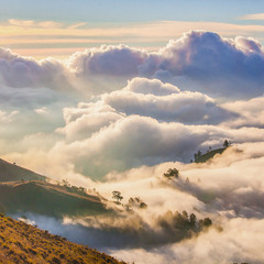 Склоны вулкана Ринджани окутанные облакми в лучах восходящего солнца