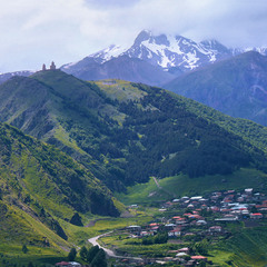 Село під горою - Степанцмінда в Сакартвело, гора в хмарах - Казбек. Хмарно з проясненням.